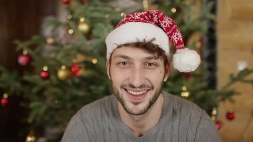 Man Wearing Santa Hat Smiling by Christmas Tree