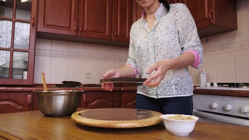 Woman Assembling Chocolate Cake in Kitchen