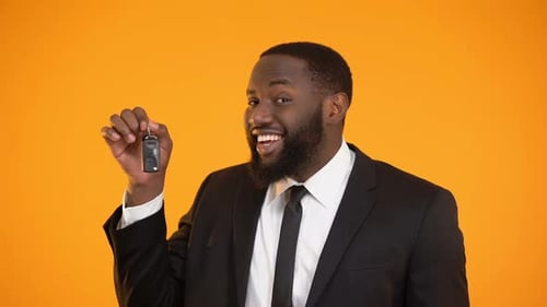 Man Holding Car Keys in Front of Orange Background