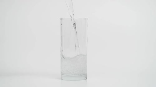 Cámara lenta de verter agua con gas en un vaso de 1000 fps sobre fondo blanco