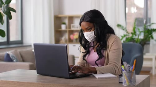 Woman in Mask with Laptop Working at Home Office