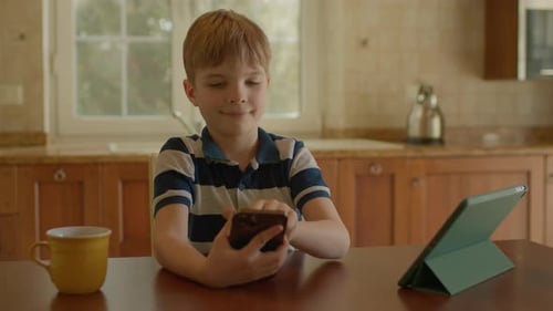 Schuljunge benutzt Handy und zeigt Greenscreen vor der Kamera