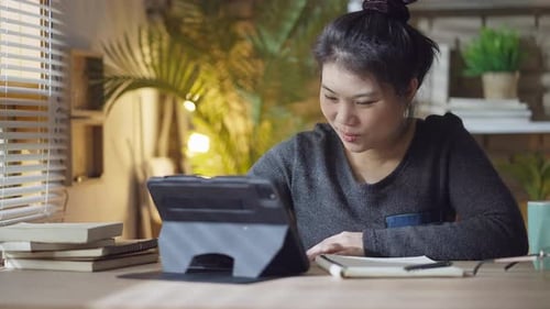 asian female wear casual cloth working form home using tablet technology device,