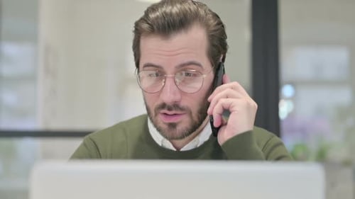 Close Up of Young Businessman with Laptop Talking on Smartphone