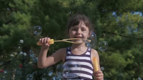Girl Having Fun Blowing Bubbles in Garden