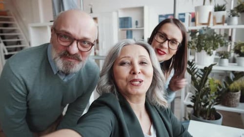 Positive Mixed-Aged Colleagues Chatting on Video Call in Office