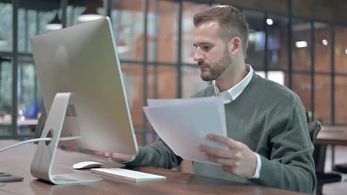 Adult Man Reviews Documents, Uses Computer in Office