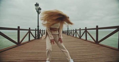 Young Woman Dancing Along Pier At Seaside