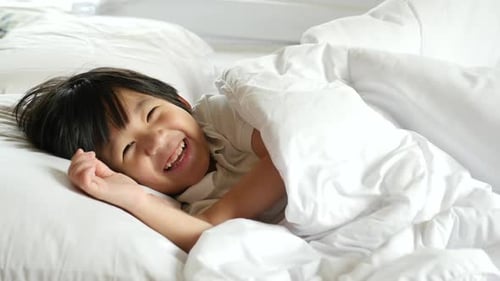 Smiling Boy Laying in White Bed