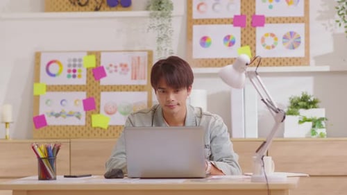 Young Man Working at Desk with Laptop Computer