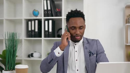 Young Black-Skinned Office Manager which Has Phone Conversation in His Contemporary office