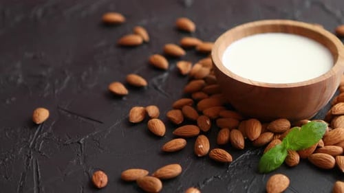 Almond Milk and Raw Almonds on Black Background