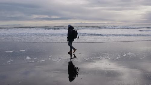 Hiker Walking Along Black Sand Beach Towards Vestrahorn Mountain