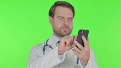 Young Doctor Browsing Smartphone on Green Background