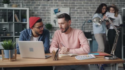 Young Men Discussing Project Looking at Laptop Screen in Creative Modern Office