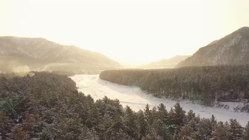 Scenery Aerial View of Winter Forest and Frozen River Katun on a Sunset Against Mountains