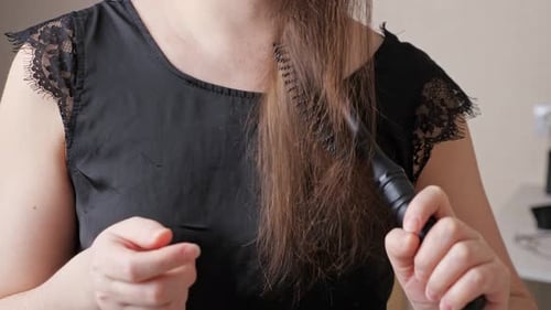 Woman Combs Brown Hair with a Hairbrush