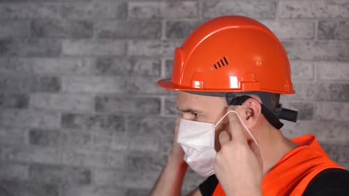 Construction Worker Puts On Protective Mask and Hardhat