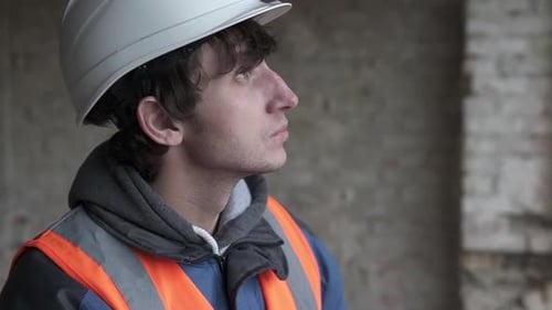A builder engineer at a construction site works with documentation and drawings.