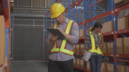 Young man and woman worker check stock and inspection with document on clipboard in the warehouse.