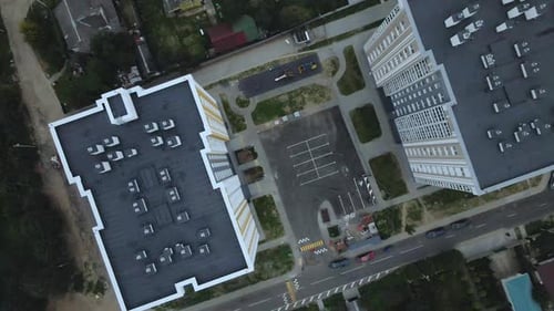 City block. Modern multi-storey buildings among cottages. Flying at dusk at sunset.