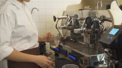 Close up of woman worker, barista in apron making a coffee by using coffee machine in kitchen bar