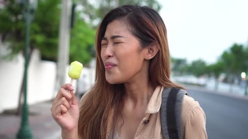 Young Woman Enjoys Popsicle on City Street