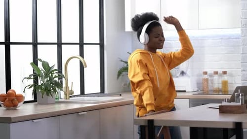 Woman Dancing with Headphones in Modern Kitchen