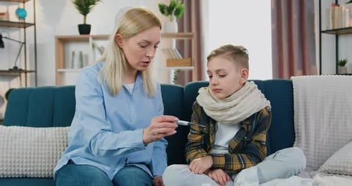 Madre habla con su triste y cansado hijo enfermo cuando le midieron la temperatura corporal