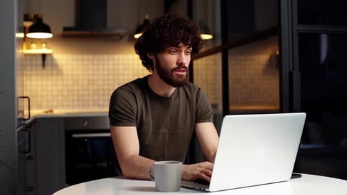 Young Adult Using Laptop in Kitchen at Night
