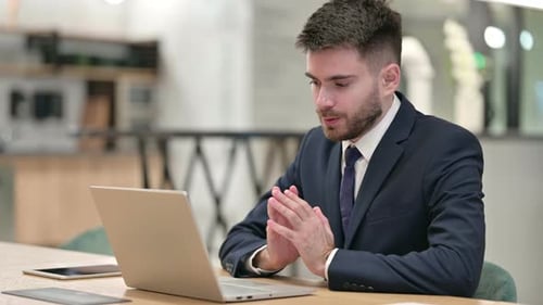 Pensive Young Businessman Thinking and Working on Laptop in Office