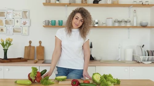 Woman Smiles in Kitchen with Fresh Vegetables