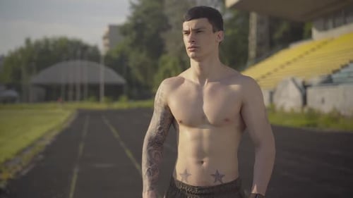 Muscular Man Drinking Water on Track Field