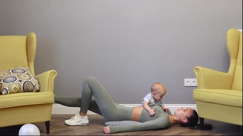 Young Slim Caucasian Mother Doing Sport Fitness Exercises Home with Baby Infant