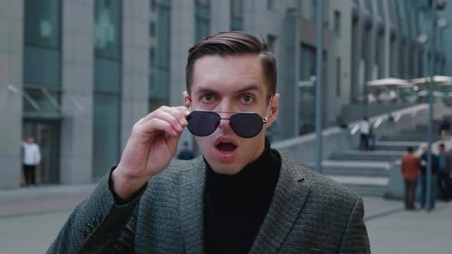 Der
schockierte junge Geschäftsmann zieht überrascht seine Sonnenbrille aus. Erstaunter Mann, der Angst vor den Nachrichten hat