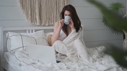 Woman in Bed Working on Laptop and Drinking Coffee