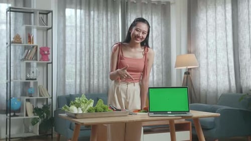 Woman Pointing Green Screen Laptop On The Table And Smiling To Camera While Preparing Healthy Food