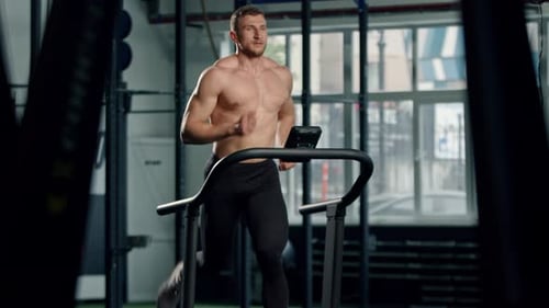 Muscular Man Running on Treadmill in Gym