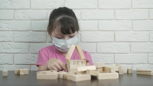 Girl Building Blocks Wearing Mask in Front of Wall