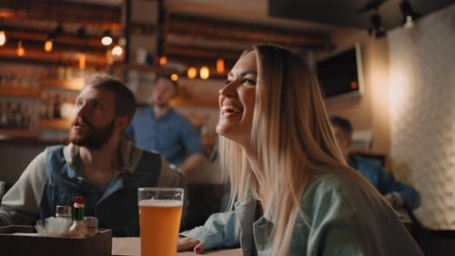 Closeup of a Group of Male and Female Friends Sitting Together in a Bar and Watching a Broadcast on