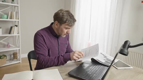 Man Works From Home With Laptop and Reports