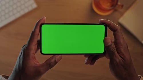 African American Man Holding Cell Phone with Green Empty Screen