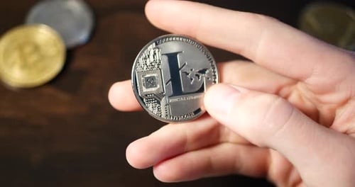 A man holding a flipping over a digital cryptocurrency litecoin as he thinks about a decentralized e