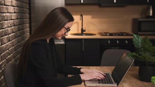 Woman Typing on Laptop in Modern Kitchen