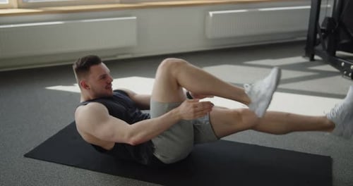 Junger muskulöser Athlet trainiert in einem modernen Fitnessstudio und macht Knie-Bauchmuskeln