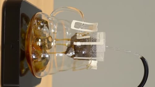 Pouring Water Through Coffee Filter Into Glass Mug