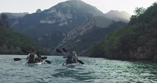 Kayakers Paddling on Lake Surrounded by Mountains