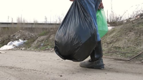 Person Walking By Landfill Carrying Garbage Bag