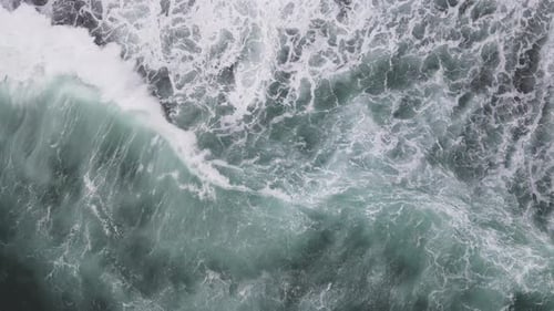 Top down aerial view of giant ocean waves crashing and foaming