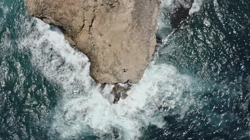Tourist Couple on Top of Cliff with Ocean Waters Sparkling Against Sun